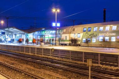 Kouvola, Finlandiya - 8 Kasım 2018: Uzun pozlama fotoğraf. Geceleri tren istasyonu üzerinde. Bulanık yolcu ile yürüyüş ve platform üzerinde kalan seyahat çantaları