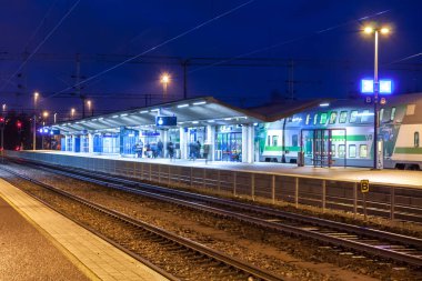 Kouvola, Finlandiya - 8 Kasım 2018: Uzun pozlama fotoğraf. Geceleri tren istasyonu üzerinde. Bulanık yolcu ile yürüyüş ve platform üzerinde kalan seyahat çantaları