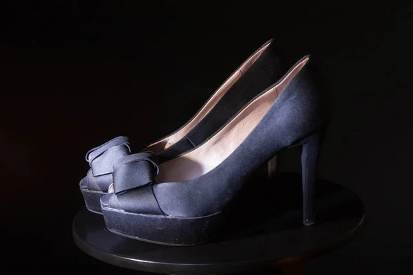 Black ladies stiletto heel pump with bow on black background.