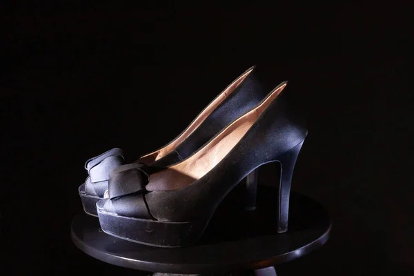 Black ladies stiletto heel pump with bow on black background.