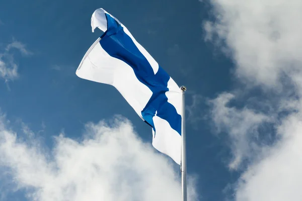 青い空と雲の背景の上に風でポールにフィンランドの国旗 — ストック写真