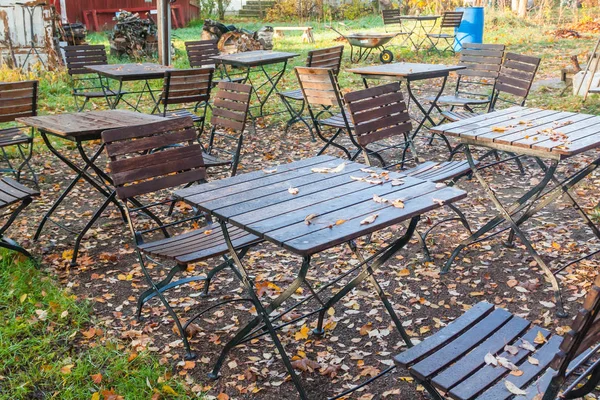 美丽的秋天在老户外咖啡馆在公园 潮湿的桌子和椅子与五颜六色的叶子 — 图库照片