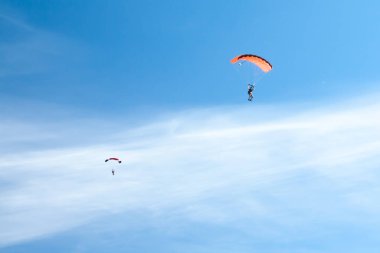 iki paraşütçü renkli paraşüt arka planı beyaz kabarık bulutlar sınırsız mavi gökyüzünde uçmak.