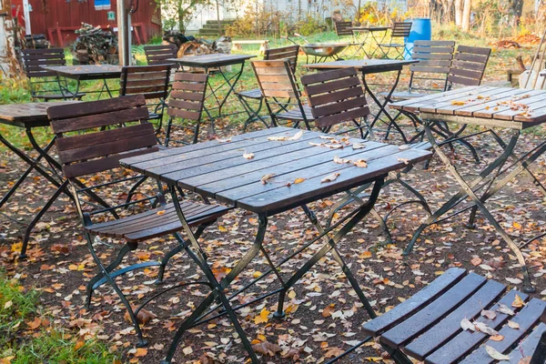 美丽的秋天在老户外咖啡馆在公园-潮湿的桌子和椅子与五颜六色的叶子. — 图库照片