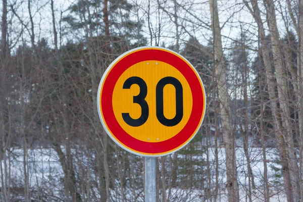 Sebességkorlátozás 30 kilométer per órás út jel-ra fák háttér-tél Finnország. — Stock Fotó