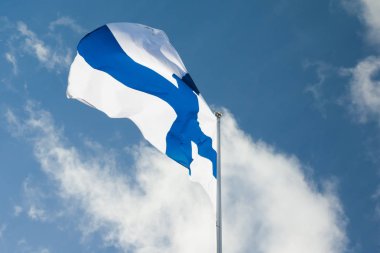 Finlandiya ulusal bayrak Rüzgar kutup mavi gökyüzü ve bulutlar arka plan üzerinde.