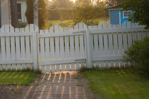 Witte houten hek met een poort op zonsondergang. — Stockfoto