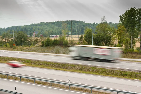 Blurred cargo car in motion. Asphalt roads with car at autumn in Finland.