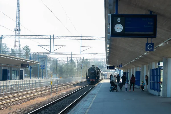 クヴォラ、フィンランド - 2019年4月18日:乗客は朝駅で蒸気機関車ウッコペッカを待っています. ストック画像