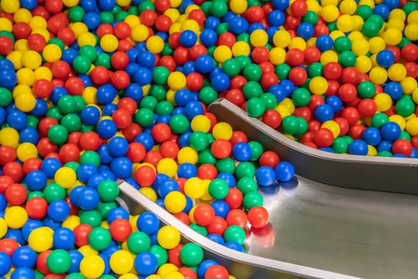 Металева дитяча гірка спускається в басейн з багатьма кольоровими кульками в дитячій кімнаті . — стокове фото