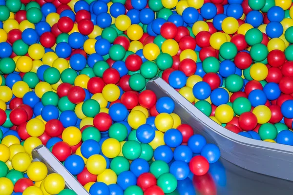 Metal baby slide going down to the pool with many colored balls in the kids playing room. — Stock Photo, Image