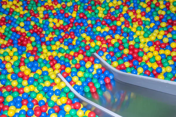 Glissière de bébé en métal descendant à la piscine avec de nombreuses boules colorées dans la salle de jeux pour enfants . — Photo