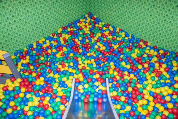 Glissière de bébé en métal descendant à la piscine avec de nombreuses boules colorées dans la salle de jeux pour enfants . — Photo