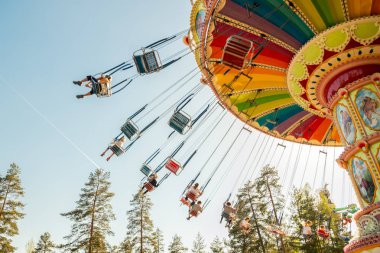 Kouvola, Finlandiya - 18 Mayıs 2019: Ride Swing Carousel hareket eğlence parkı Tykkimaki ve gökyüzünde uçak izi.