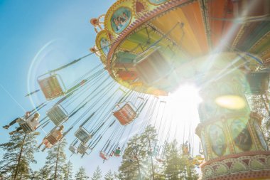 Kouvola, Finlandiya - 18 Mayıs 2019: Ride Swing Carousel hareket eğlence parkı Tykkimaki ve gökyüzünde uçak izi.