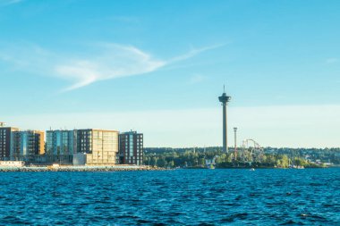 Tampere, Finlandiya - 24 Haziran 2019: Nasinneula kulesine sahip Sarkanniemi eğlence parkı, gün batımında su manzarası