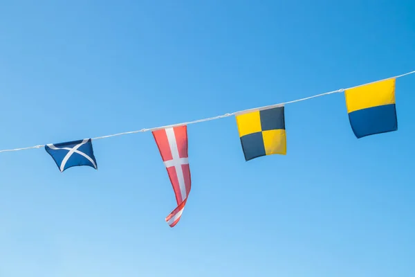 Námořní vlajky na lodi proti modrému nebi — Stock fotografie