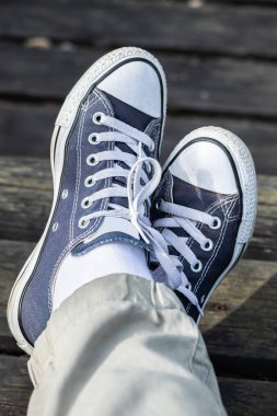 Ahşap arka planda ayaklarda mavi spor ayakkabılar. Üstte görüntü.