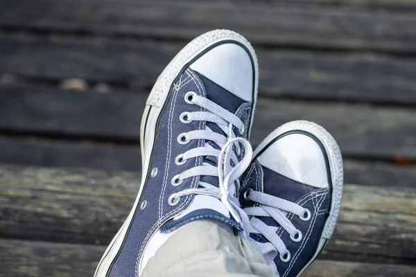 Blue sneakers on the feet on wooden background. Top view. — Stock Photo, Image