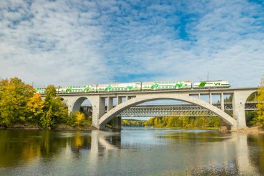 Kouvola, Finlandiya - 25 Eylül 2019: Finlandiya, Kymenlaakso, Kouvola, Koria 'da hareket eden yolcu treni ve Kymijoki nehri sularıyla birlikte sonbahar manzarası