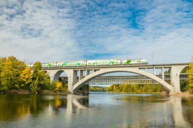 Kouvola, Finlandiya - 25 Eylül 2019: Finlandiya, Kymenlaakso, Kouvola, Koria 'da hareket eden yolcu treni ve Kymijoki nehri sularıyla birlikte sonbahar manzarası