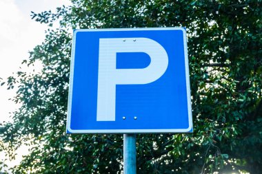 Gökyüzü ve ağaç arka plan üzerinde mavi park yol işareti