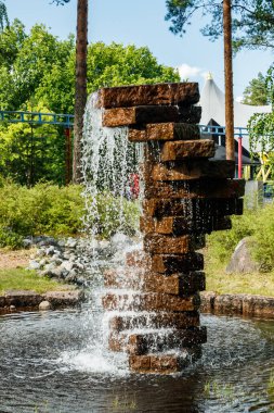 Fountain made of stones in the summer park clipart