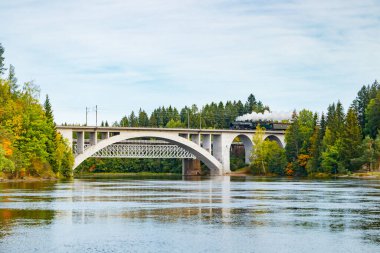 Kouvola, Finlandiya - 18 Eylül 2020: Finlandiya, Kouvola, Koria 'da eski buharlı yolcu treni Ukko-Pekka ve Kymijoki nehir sularının taşındığı bir köprü manzarası