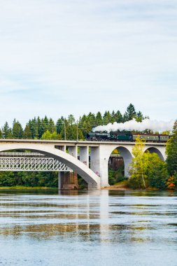 Kouvola, Finlandiya - 18 Eylül 2020: Finlandiya, Kouvola, Koria 'da eski buharlı yolcu treni Ukko-Pekka ve Kymijoki nehir sularının taşındığı bir köprü manzarası