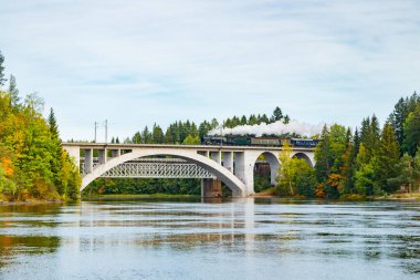 Kouvola, Finlandiya - 18 Eylül 2020: Finlandiya, Kouvola, Koria 'da eski buharlı yolcu treni Ukko-Pekka ve Kymijoki nehir sularının taşındığı bir köprü manzarası