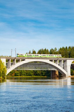 Finlandiya, Kouvola, Koria 'da hareket eden yolcu treni ve Kymijoki nehir suları ile sonbahar manzarası