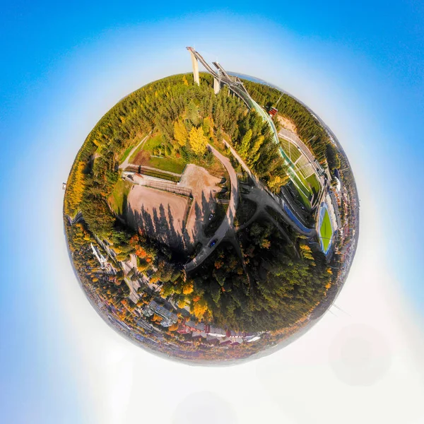 A three dimensional aerial panoramic view of Lahti sports centre with three ski jump towers, in a mini planet panorama style.