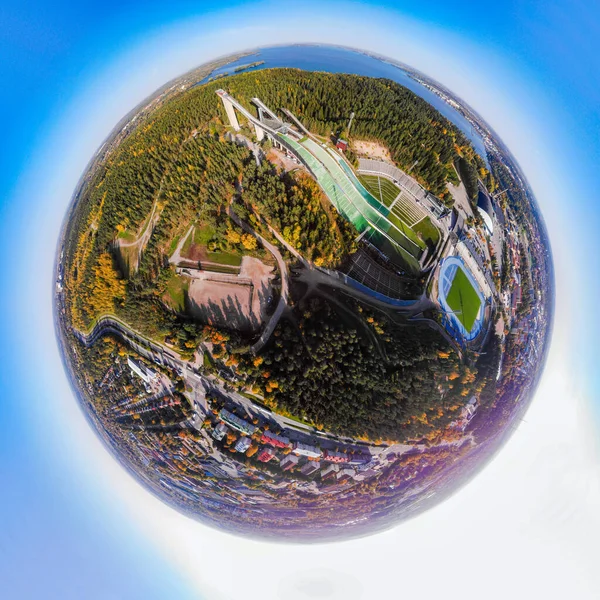 A three dimensional aerial panoramic view of Lahti sports centre with three ski jump towers, in a mini planet panorama style.