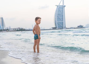 Küçük denizde oynarken oğlu gülümseyen portre okyanus. Olumlu insan duyguları, duygular, joy. Tatil yapma ve yaz zevk komik şirin çocuk. Günbatımı Dubai plaj.