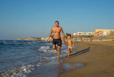 Baba ve oğul kumsalda oynarken, kalite aile zaman yiyorsunuz. Yunanistan.
