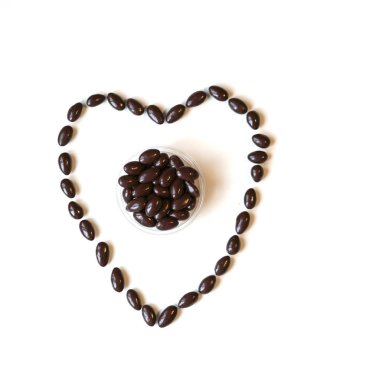 Fındık arka plan üzerinde kalp şeklinde düzenlenmiştir. Gıda görüntü yakın şeker, çikolatalı süt, ekstra koyu badem fındık kadar. Beyaz gri masa üstü görünümü üzerinde doku seviyorum