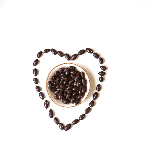 Nuts arranged in heart shape on background. Food image close up candy, chocolate milk, extra dark almond nuts. Love Texture on white grey table top view — Stock Photo, Image