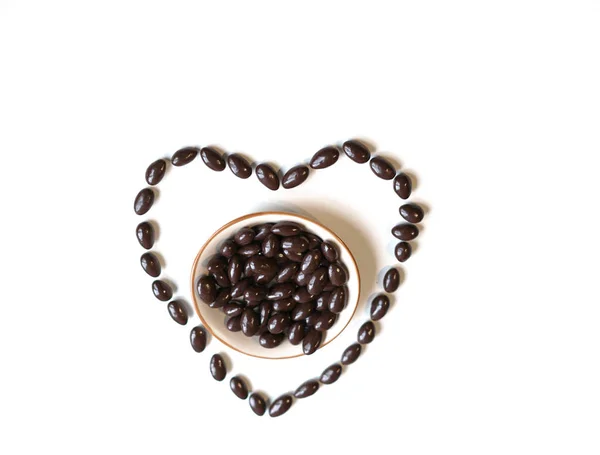 Nuts arranged in heart shape on background. Food image close up candy, chocolate milk, extra dark almond nuts. Love Texture on white grey table top view — Stock Photo, Image