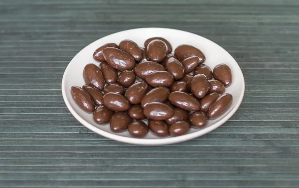 Lebensmittel Bild Nahaufnahme Bonbons, Schokoladenmilch, extra dunkle Mandelnüsse. Textur auf dem Hintergrund auf dem Teller — Stockfoto