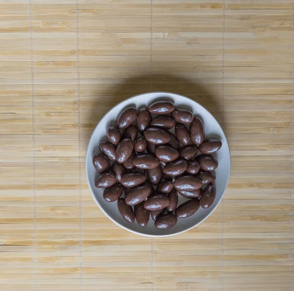 Imagen de la comida cerrar caramelos, leche de chocolate, nueces de almendras oscuras extra. Textura en el fondo de la vista en el plato de copa — Foto de Stock