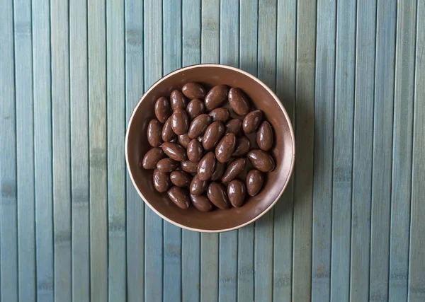 Imagen de la comida cerrar caramelos, leche de chocolate, nueces de almendras oscuras extra. Textura en el fondo de la vista en el plato de copa — Foto de Stock