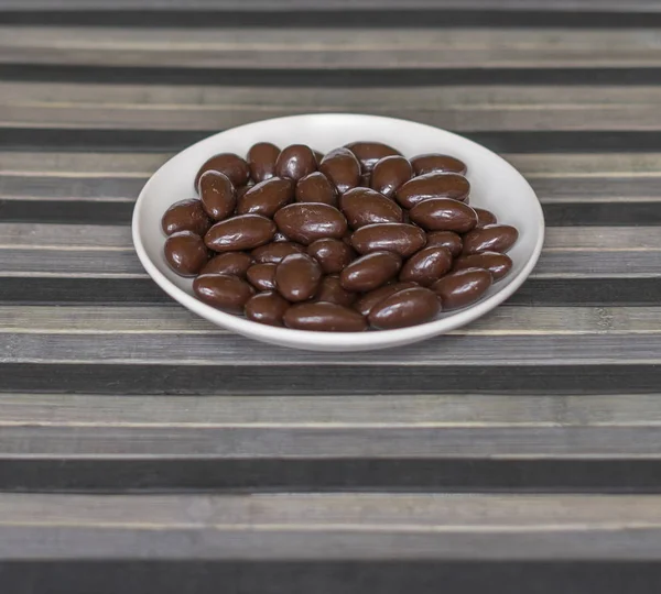 Imagen de la comida cerrar caramelos, leche de chocolate, nueces de almendras oscuras extra. Textura en el fondo de la vista en el plato de copa — Foto de Stock