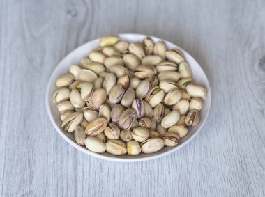 Arka plan görüntüsü için sağlıklı gıda antep fıstığı kapatın. Beyaz gri masa üstü görünümünde doku. Fincan tabağı üzerinde fındık antep fıstığı