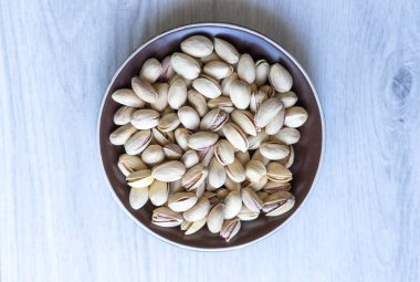 Arka plan görüntüsü için sağlıklı gıda antep fıstığı kapatın. Beyaz gri masa üstü görünümünde doku. Fincan tabağı üzerinde fındık antep fıstığı