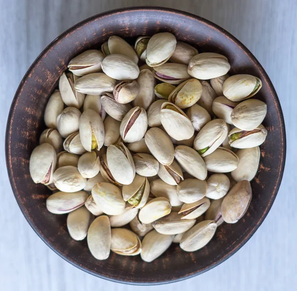 Arka plan görüntüsü için sağlıklı gıda antep fıstığı kapatın. Beyaz gri masa üstü görünümünde doku. Fincan tabağı üzerinde fındık antep fıstığı