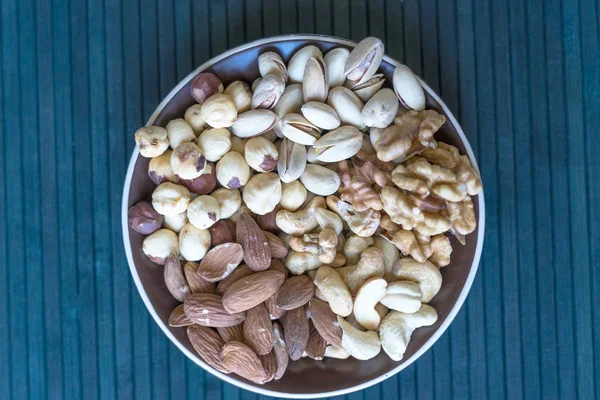 健康的な食べ物 ナットは 石のテクスチャトップビュー上の品揃えをミックスします 背景画像クローズアップナッツ ピスタチオ アーモンド カシューナッツ ピーナッツ クルミのための異なる豆のコレクション イメージ — ストック写真