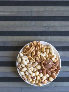 Sağlıklı yiyecekler. Taş doku üst görünümünde fındık karışımı çeşitler. Arka plan görüntüsü için farklı baklagiller koleksiyonu fındık, fıstık, badem, kaju fıstığı, fıstık, ceviz yakın. Görüntü