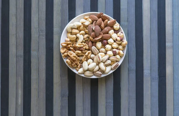 Sağlıklı yiyecekler. Taş doku üst görünümünde fındık karışımı çeşitler. Arka plan görüntüsü için farklı baklagiller koleksiyonu fındık, fıstık, badem, kaju fıstığı, fıstık, ceviz yakın. Görüntü