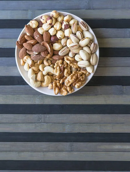 健康的な食べ物 ナットは 石のテクスチャトップビュー上の品揃えをミックスします 背景画像クローズアップナッツ ピスタチオ アーモンド カシューナッツ ピーナッツ クルミのための異なる豆のコレクション イメージ — ストック写真