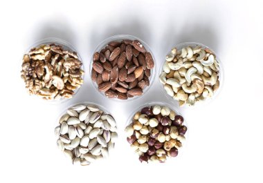 Sağlıklı yiyecekler. Somunlar beyaz gri masa üstü görünümünde çeşitli karıştırın. Arka plan görüntüsü için farklı baklagiller koleksiyonu yakın fındık, antep fıstığı, badem, kaju fıstığı, fıstık, ceviz. Görüntü